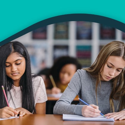 Teenage students writing in notebooks in a classroom