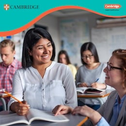 Female student in a classroom smiles at teacher who is helping her