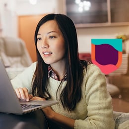 Young woman working at her laptop with the Cambridge Shield in the background.