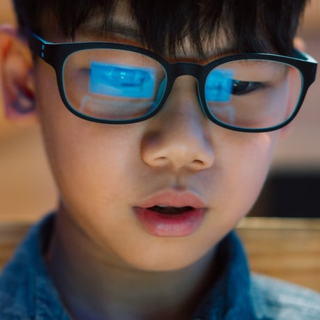 Young boy with computer reflection on his glasses