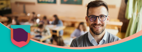 Male teacher in a classroom smiling at the camera