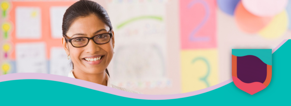 Female teacher in a classroom smiling at the camera