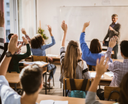 Teenage students interacting with a male teacher in a classroom